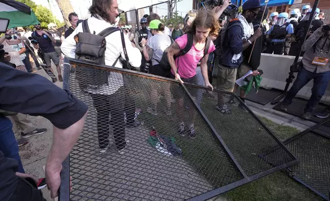 Protesters knock down a fence surrounding United Center at the Democratic National Convention after a march Monday, Aug. 19, 2024, in Chicago. (AP Photo/Alex Brandon)