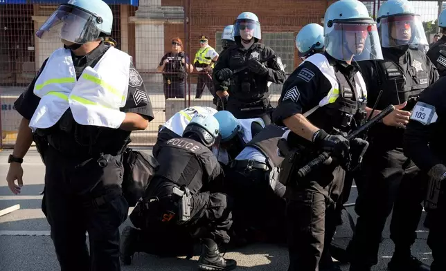 Police take a protester into custody after a fence surrounding United Center was knock down at the Democratic National Convention after a march Monday, Aug. 19, 2024, in Chicago. (AP Photo/Frank Franklin II)