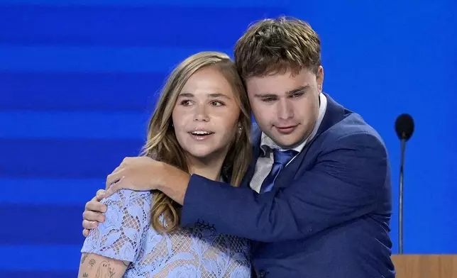 Hope Walz, left, and Gus Walz, children of Democratic vice presidential nominee Minnesota Gov. Tim Walz, right, hug after their father concludes a speech during the Democratic National Convention Wednesday, Aug. 21, 2024, in Chicago. (AP Photo/J. Scott Applewhite)