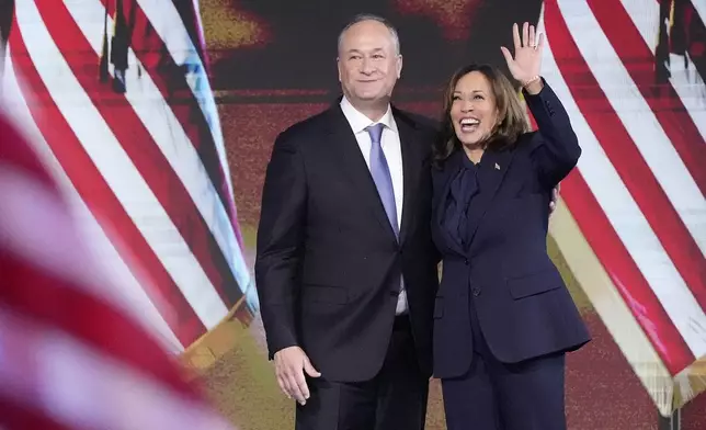 Second gentleman Doug Emhoff, left, looks on as Democratic presidential nominee Vice President Kamala Harris waves at the conclusion of her speech during the Democratic National Convention Thursday, Aug. 22, 2024, in Chicago. (AP Photo/J. Scott Applewhite)