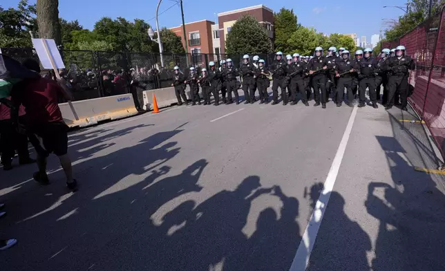 Police walk towards protesters who knock down a fence surrounding United Center at the Democratic National Convention after a march Monday, Aug. 19, 2024, in Chicago. (AP Photo/Alex Brandon)