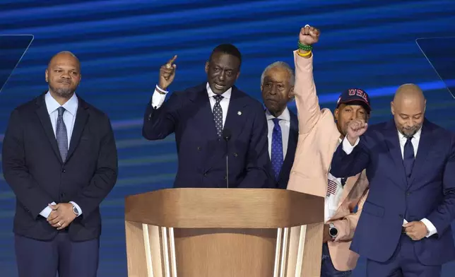 Rev. Al Sharpton, background center, looks on as members of The Exonerated Five, Korey Wise, from left, Yusef Salaam, Kevin Richardson and Raymond Santana speak during the Democratic National Convention Thursday, Aug. 22, 2024, in Chicago. (AP Photo/J. Scott Applewhite)