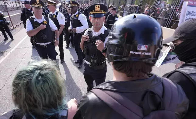 Police walk towards protesters who knock down a fence surrounding United Center at the Democratic National Convention after a march Monday, Aug. 19, 2024, in Chicago. (AP Photo/Alex Brandon)