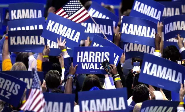 Supporters carry signs as Democratic presidential nominee Vice President Kamala Harris speaks during the Democratic National Convention Thursday, Aug. 22, 2024, in Chicago. (AP Photo/J. Scott Applewhite)