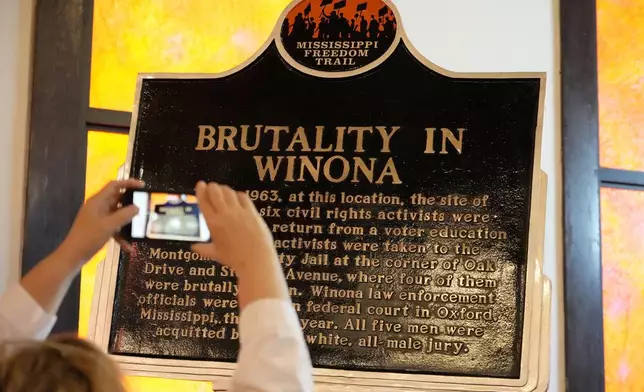 An attendee takes a cell phone photo, June 8, 2024, following the unveiling in Winona, Miss., of a Mississippi Freedom Trail marker commemorating the brutality faced by Fannie Lou Hamer and other civil rights activists who were arrested in June 1963, at a bus station in Winona as they returned from an out-of-state citizenship training session. (AP Photo/Rogelio V. Solis)