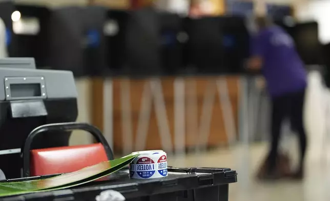 Stickers reading "I voted" rest beside a ballot scanner as a voter fills in a ballot at a privacy booth, during voting in Florida's primary election, Tuesday, Aug. 20, 2024, in a voting bureau at the American Legion in South Miami, Fla. (AP Photo/Rebecca Blackwell)