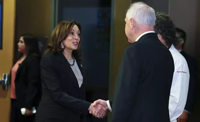 FILE - Vice President Kamala Harris greets Governor Tim Walz, right, at Planned Parenthood, March 14, 2024, in St. Paul, Minn. (AP Photo/Adam Bettcher, file )