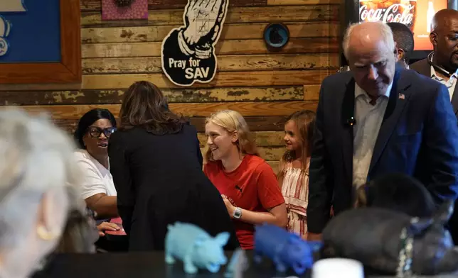 Democratic presidential nominee Vice President Kamala Harris and her running mate Minnesota Gov. Tim Walz talk as they visit SandFly Bar-B-Q in Savannah, Ga., Wednesday, Aug. 28, 2024. (AP Photo/Jacquelyn Martin)