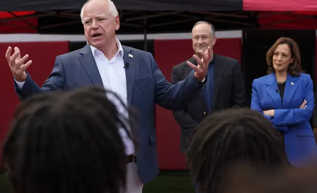 Democratic vice presidential nominee Minnesota Gov. Tim Walz speaks as Democratic presidential nominee Vice President Kamala Harris, right, and second gentleman Doug Emhoff listen during a campaign stop to greet members of the Aliquippa High School football team at their school, Sunday, Aug. 18, 2024, in Aliquippa, Pa. (AP Photo/Julia Nikhinson)