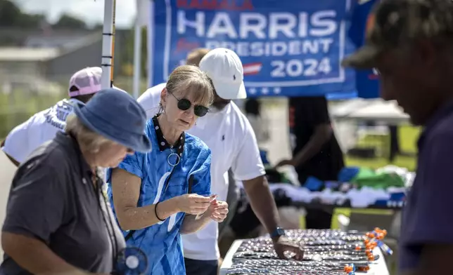 Cynthia Corey, from Brunswick, Ga., buys a Harris button from an vendor outside a venue where democratic presidential nominee Vice President Kamala Harris is planned to speak during a campaign event, Thursday, Aug. 29, 2024, in Savannah, Ga. (AP Photo/Stephen B. Morton)