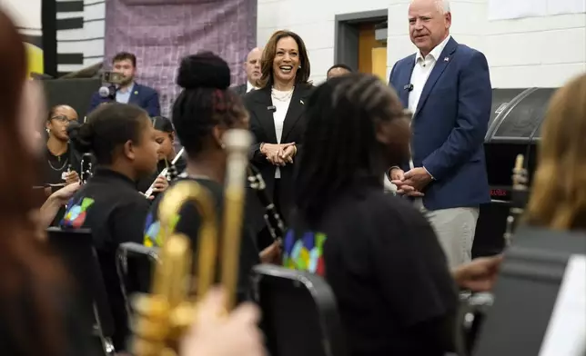 Democratic presidential nominee Vice President Kamala Harris and Democratic vice presidential candidate Minnesota Gov. Tim Walz speak to marching band members at Liberty County High School in Hinesville, Ga., Wednesday, Aug. 28, 2024. (AP Photo/Jacquelyn Martin)