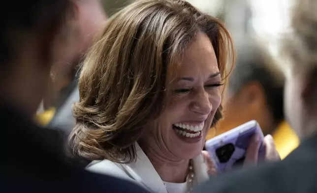 Democratic presidential nominee Vice President Kamala Harris talks with the daughter of a supporter on the phone as she makes a stop at a volunteer appreciation event at The Gray in downtown Savannah, Ga., Thursday, Aug. 29, 2024. (AP Photo/Jacquelyn Martin)