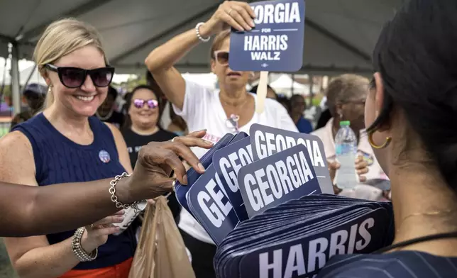 Supporters for democratic presidential nominee Vice President Kamala Harris grab fans to try to stay cool outside a campaign event, Thursday, Aug. 29, 2024, in Savannah, Ga. (AP Photo/Stephen B. Morton)