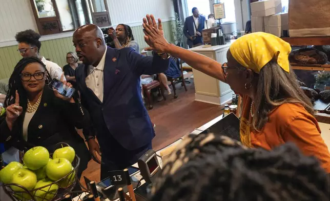 Savannah Mayor Van Johnson high-fives an employee as Rep. Nikema Williams, D-Ga., watches as Democratic presidential nominee Vice President Kamala Harris visits Dottie's Market in Savannah, Ga., Thursday, Aug. 29, 2024. (AP Photo/Jacquelyn Martin)