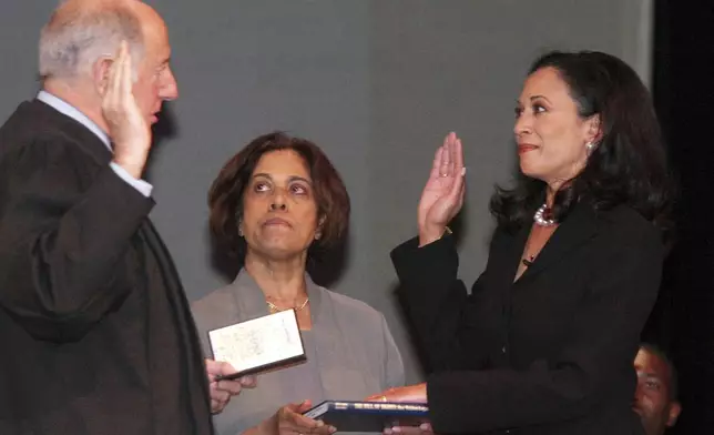 FILE - San Francisco's new district attorney, Kamala Harris, right, with her mother Dr. Shyamala Gopalan holding a copy of The Bill of Rights, receives the oath of office from California Supreme Court Chief Justice Ronald M. George, left, during inauguration ceremonies, Jan. 8, 2004, in San Francisco. (AP Photo/George Nikitin, File)