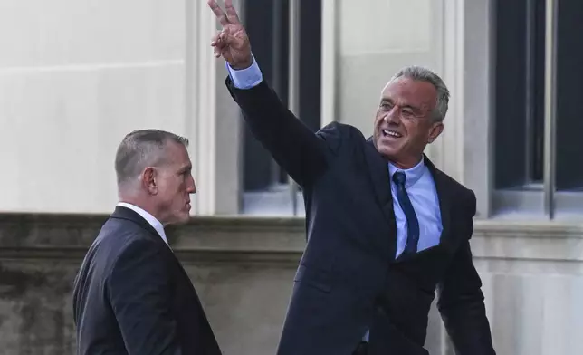 Independent presidential candidate Robert F. Kennedy Jr., right, waves to a group of supporters as he arrives at the Albany County Courthouse to fight a lawsuit he falsely claimed to live in New York state, Wednesday, Aug. 7, 2024, in Albany, N.Y. (AP Photo/Hans Pennink)