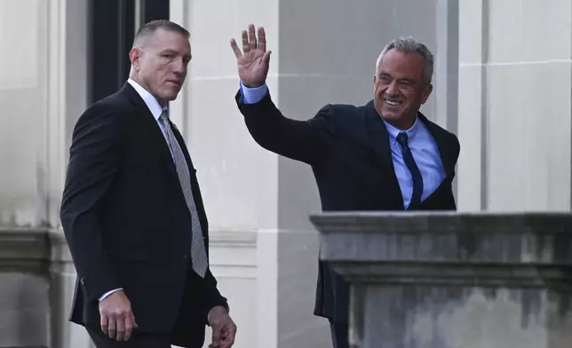 Independent presidential candidate Robert F. Kennedy Jr., right, waves to a group of supporters as he arrives at the Albany County Courthouse to fight a lawsuit he falsely claimed to live in New York state, Wednesday, Aug. 7, 2024, in Albany, N.Y. (AP Photo/Hans Pennink)