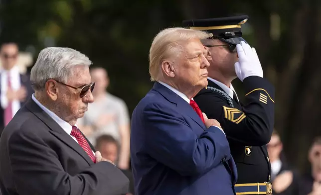 Bill Barnett, left, grandfather of Darin Taylor Hoover, and Republican presidential nominee former President Donald Trump place their hands over their heart after placing a wreath at the Tomb of the Unknown Solider in honor of Staff Sgt. Darin Taylor Hoover at Arlington National Cemetery, Monday, Aug. 26, 2024, in Arlington, Va. (AP Photo/Alex Brandon)