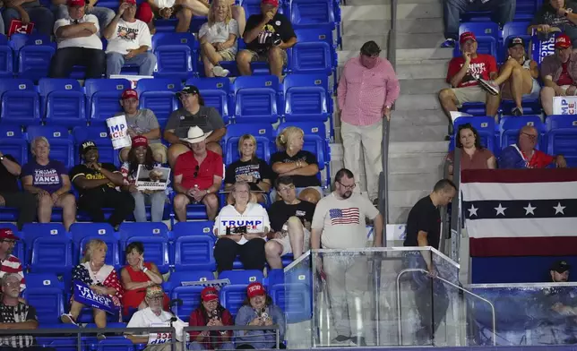 Attendees walk in the aisles as Republican presidential candidate former President Donald Trump speaks at a campaign rally at Georgia State University in Atlanta, Saturday, Aug. 3, 2024. (AP Photo/Ben Gray)