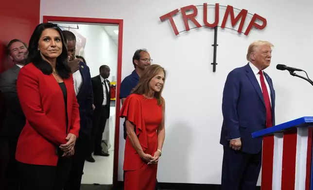 Former Rep. Tulsi Gabbard of Hawaii, left, and Rep. Lisa McClain, R-Mich., third from right, look on as Republican presidential nominee former President Donald Trump speaks during a stop at a campaign office, Monday, Aug. 26, 2024, in Roseville, Mich. (AP Photo/Carolyn Kaster)