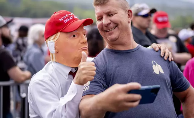 A supporter takes a selfie with a person wearing a Donald Trump mask before a campaign rally for Republican presidential nominee former President Trump at the Mohegan Sun Arena at Casey Plaza in Wilkes-Barre, Pa., Saturday, Aug. 17, 2024. (AP Photo/Laurence Kesterson)