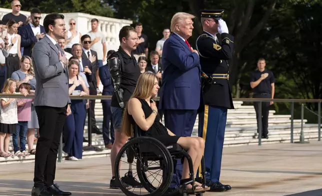 Marlon Bateman, left, former U.S. Marine Sgt. Tyler Vargas, former U.S. Marine Cpl. Kelsee Lainhart, center front, and Republican presidential nominee former President Donald Trump place their hands over their heart after placing a wreath at the Tomb of the Unknown Solider in honor of the 13 service members killed at Abbey Gate, at Arlington National Cemetery, Monday, Aug. 26, 2024, in Arlington, Va. (AP Photo/Alex Brandon)