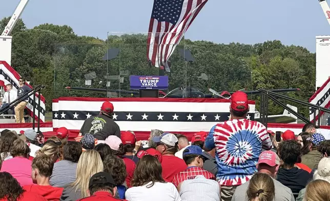 An outdoor stage is set encased with bulletproof glass as supporters arrive to hear Republican presidential nominee former President Donald Trump speak at a rally, Wednesday, Aug. 21, 2024, in Asheboro, N.C. Trump is holding his first outdoor rally since narrowly surviving an attempted assassination when a a gunman opened fire in Pennsylvania last month. (AP Photo/Michelle Price)