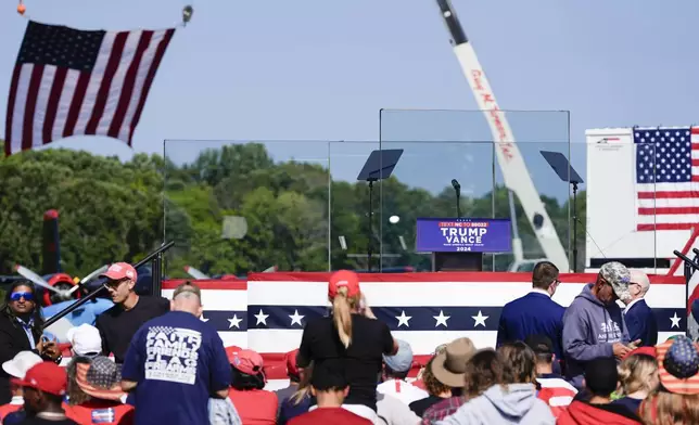 An outdoor stage is set encased with bulletproof glass as supporters arrive to hear Republican presidential nominee former President Donald Trump speak at a rally, Wednesday, Aug. 21, 2024, in Asheboro, N.C. Trump is holding his first outdoor rally since narrowly surviving an attempted assassination when a a gunman opened fire in Pennsylvania last month. (AP Photo/Julia Nikhinson)