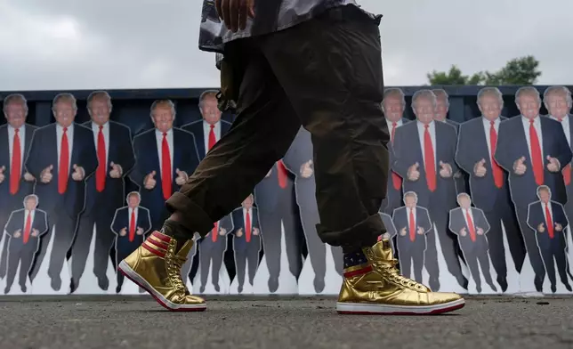 A person walks past cardboard cutouts of Republican presidential nominee former President Donald Trump before a campaign rally at the Mohegan Sun Arena at Casey Plaza, Saturday, Aug. 17, 2024, in Wilkes-Barre, Pa. (AP Photo/Carolyn Kaster)