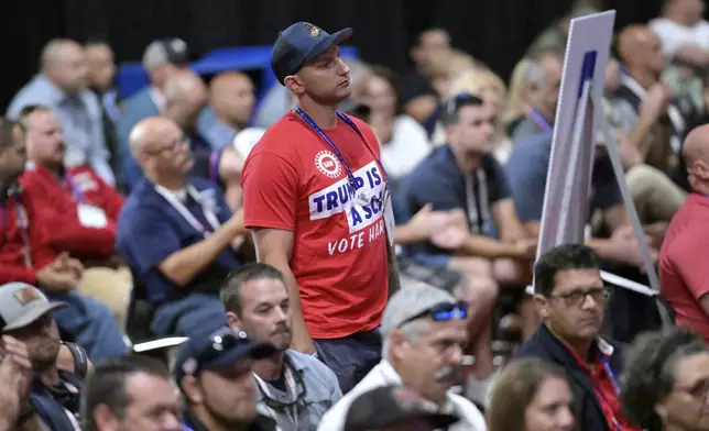 A man in a shirt expressing opposition to the candidacy of Donald Trump stands as Republican vice presidential nominee Sen. JD Vance, R-Ohio, speaks at the International Association of Fire Fighters Convention on Thursday, Aug. 29, 2024, in Boston. (AP Photo/Josh Reynolds)