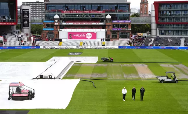 Umpires inspect the pitch as ground staff remove the rain covers during day two of the First Rothesay Test match at the Emirates Old Trafford, Manchester, Thursday Aug. 22, 2024. (Nick Potts/PA via AP)