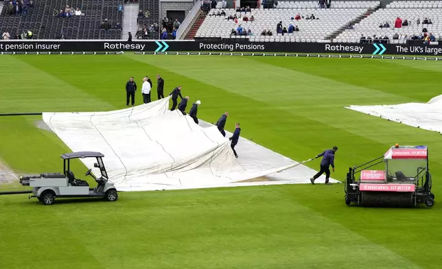 Umpires inspect the pitch as ground staff remove the rain covers during day two of the First Rothesay Test match at the Emirates Old Trafford, Manchester, Thursday Aug. 22, 2024. (Nick Potts/PA via AP)