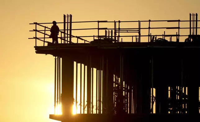 Construction workers start their day as the sun rises on the new Republic Airlines headquarters building in Carmel, Ind., Tuesday, Aug. 27, 2024. (AP Photo/Michael Conroy)