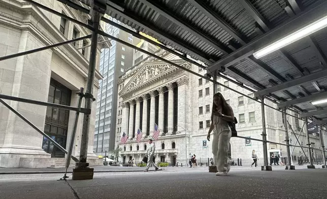 People pass the New York Stock Exchange, at rear, on Tuesday, Aug. 27, 2024, in New York. (AP Photo/Peter Morgan)