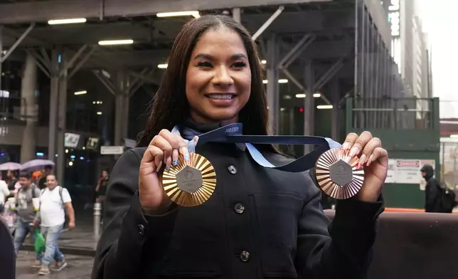 Two-time U.S. Olympic gymnast medalist Jordan Chiles shows her medals after ringing the closing bell at the Nasdaq MarketSite, in New York's Times Square, Thursday, Aug. 8, 2024. (AP Photo/Richard Drew)