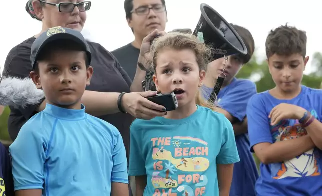 Helena Lourenco, center, 8, speaks out during a protest against Gov. Ron DeSantis' plan to develop state parks with business ventures such as golf courses, pickleball courts and large hotels, during a demonstration at Oleta River State Park, Tuesday, Aug. 27, 2024, in North Miami Beach, Fla. (AP Photo/Wilfredo Lee)