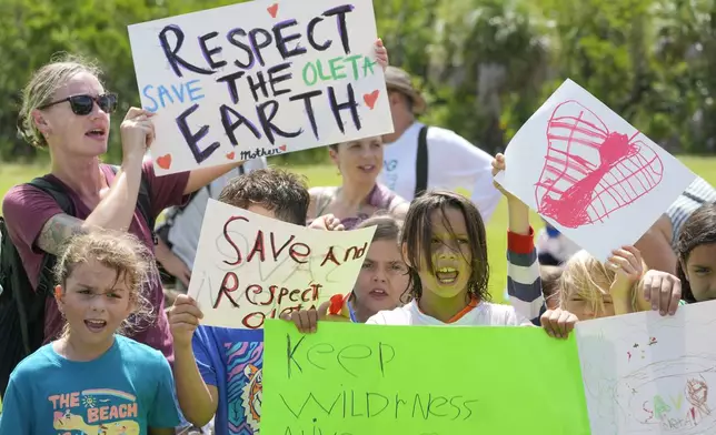 Protesters chant against Gov. Ron DeSantis' plan to develop state parks with business ventures such as golf courses, pickleball courts and large hotels, during a demonstration at Oleta River State Park, Tuesday, Aug. 27, 2024, in North Miami Beach, Fla. (AP Photo/Wilfredo Lee)