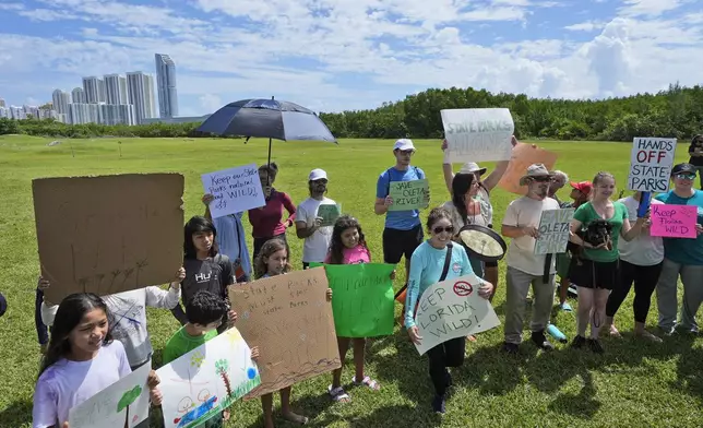 Demonstrators chant during a protest against Gov. Ron DeSantis' plan to develop state parks with business ventures such as golf courses, pickleball courts and large hotels, at Oleta River State Park, Tuesday, Aug. 27, 2024, in North Miami Beach, Fla. (AP Photo/Wilfredo Lee)