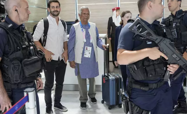 Nobel laureate Muhammad Yunus stands with his luggage at the check-in desk at Charles de Gaulle's airport in Roissy, north of Paris, Wednesday, Aug. 7, 2024. (AP Photo/Michel Euler)