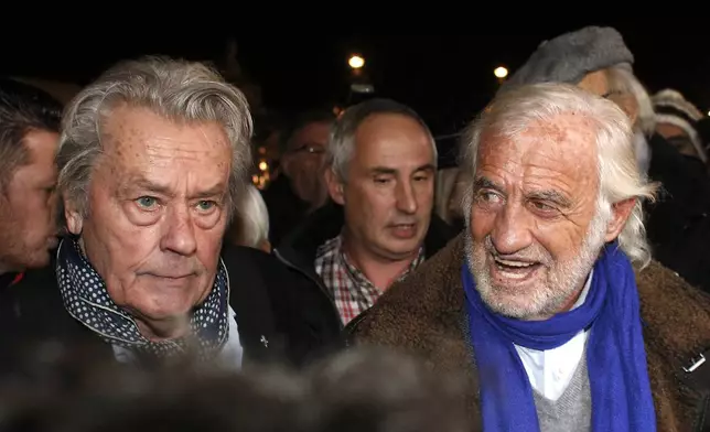 FILE - French actors Alain Delon, left, and Jean-Paul Belmondo, right, arrive for the inauguration of a giant Ferris wheel, in Paris on Nov. 17, 2017. Alain Delon, the internationally acclaimed French actor who embodied both the bad guy and the policeman and made hearts throb around the world, has died at age 88, French media reported. (AP Photo/Thibault Camus, File)