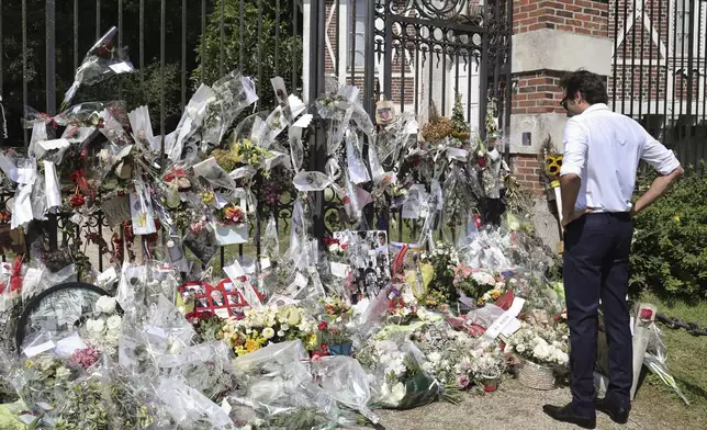 French actor Alain Delon's son Anthony Delon stands in front of the flowers and messages display at the entrance of of his father property, in Douchy, central France, Saturday, Aug. 24, 2024. (AP Photo/Thibault Camus)