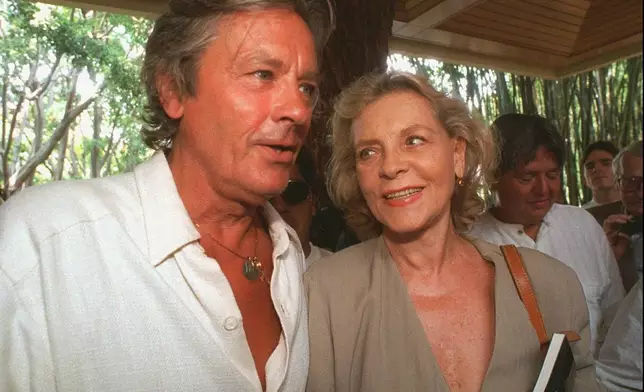 FILE - French actor Alain Delon and actress Lauren Bacall talk as they leave a news conference in the city of Cuernavaca, state of Morelos, Mexico on May 25, 1966. Alain Delon, the internationally acclaimed French actor who embodied both the bad guy and the policeman and made hearts throb around the world, has died at age 88, French media reported. (AP Photo/Dario Lopez-Mills, File)