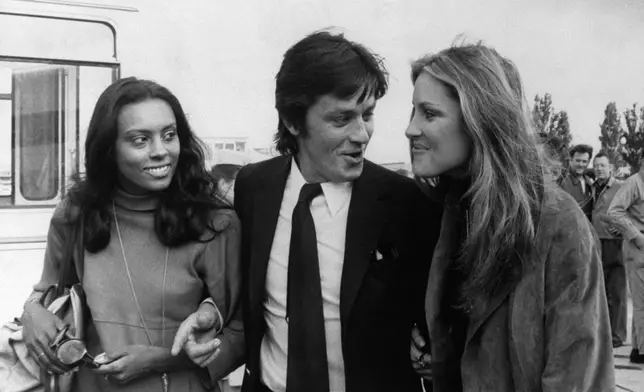 FILE - French actor Alain Delon is escorted by American actresses Jane Davenport, left, and Pamela Huntington after their arrival from New York at Orly airport in Paris on Aug.19, 1970. Alain Delon, the internationally acclaimed French actor who embodied both the bad guy and the policeman and made hearts throb around the world, has died at age 88, French media reported. (AP Photo/Laurent Rebours, File)