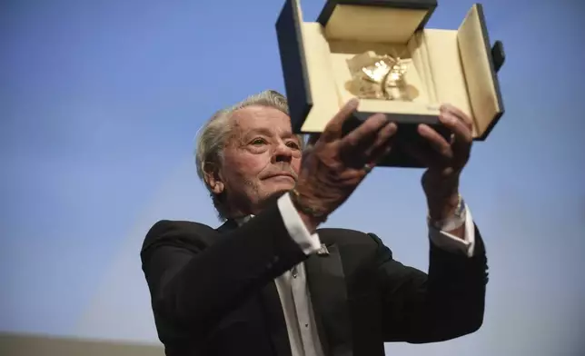 FILE - Actor Alain Delon holds aloft his honorary Palme D'Or award at the 72nd international film festival, Cannes, southern France, Sunday, May 19, 2019. Alain Delon, the internationally acclaimed French actor who embodied both the bad guy and the policeman and made hearts throb around the world, has died at age 88, French media reported. (Photo by Arthur Mola/Invision/AP)