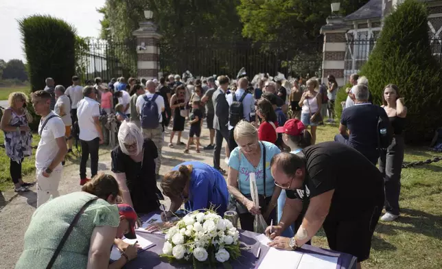 People write in a book of condolence as they pay tribute to late French actor Alain Delon, at the entrance gate of Delon's property, in Douchy, central France, Saturday, Aug. 24, 2024. (AP Photo/Thibault Camus)