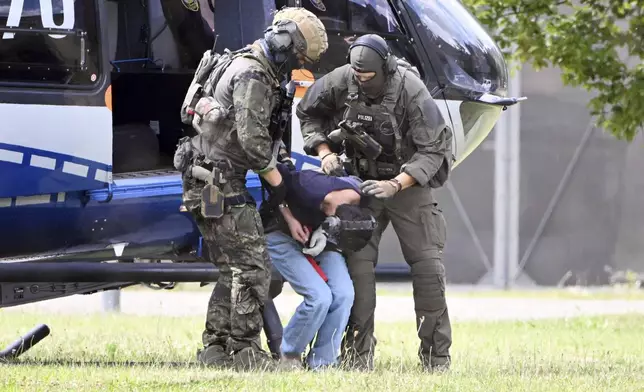 The alleged perpetrator of the knife attack in Solingen is escorted from a helicopter in Karlsruhe, Germany, Sunday, Aug. 25, 2024. German police say a 26-year-old man has turned himself in, saying he was responsible for the deadly Solingen knife attack that left three dead and eight wounded at a festival marking the city’s 650th anniversary. (Uli Deck/dpa via AP)