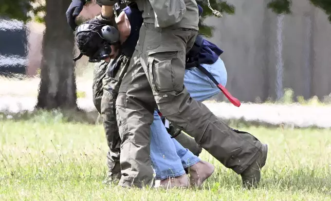 The alleged perpetrator of the knife attack in Solingen is escorted from a helicopter in Karlsruhe, Germany, Sunday, Aug. 25, 2024. German police say a 26-year-old man has turned himself in, saying he was responsible for the deadly Solingen knife attack that left three dead and eight wounded at a festival marking the city’s 650th anniversary. (Uli Deck/dpa via AP)