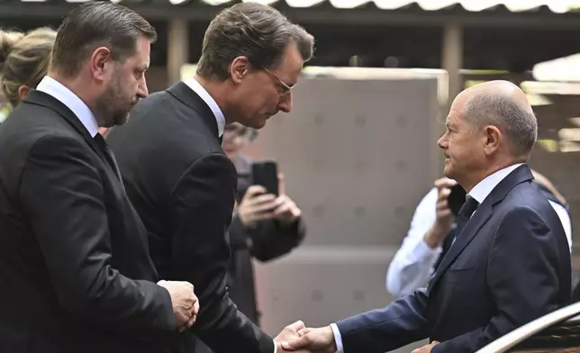 Germany Chancellor Olaf Scholz, right, is greeted by Hendrik Wüst, center, Minister President of North Rhine-Westphalia, and Tim Kurzbach, left, Mayor of Solingen, as he visits the scene of a knife attack, in Solingen, Germany, Monday, Aug. 26, 2024. (Henning Kaiser/Pool Photo via AP)