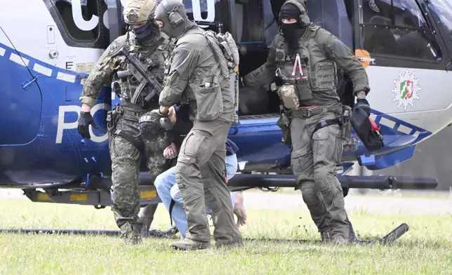 The alleged perpetrator of the knife attack in Solingen is escorted from a helicopter in Karlsruhe, Germany, Sunday, Aug. 25, 2024. German police say a 26-year-old man has turned himself in, saying he was responsible for the deadly Solingen knife attack that left three dead and eight wounded at a festival marking the city’s 650th anniversary. (Uli Deck/dpa via AP)