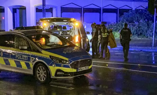 Late in the evening, a man concealed behind police officers turns himself in to the police on the street and claims to be the perpetrator of the attack at a festival in Solingen, Germany, Saturday, Aug. 24, 2024. (Christoph Reichwein/dpa via AP)